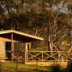 A wooden cabin, in a bush setting.