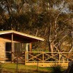 A wooden cabin, in a bush setting.
